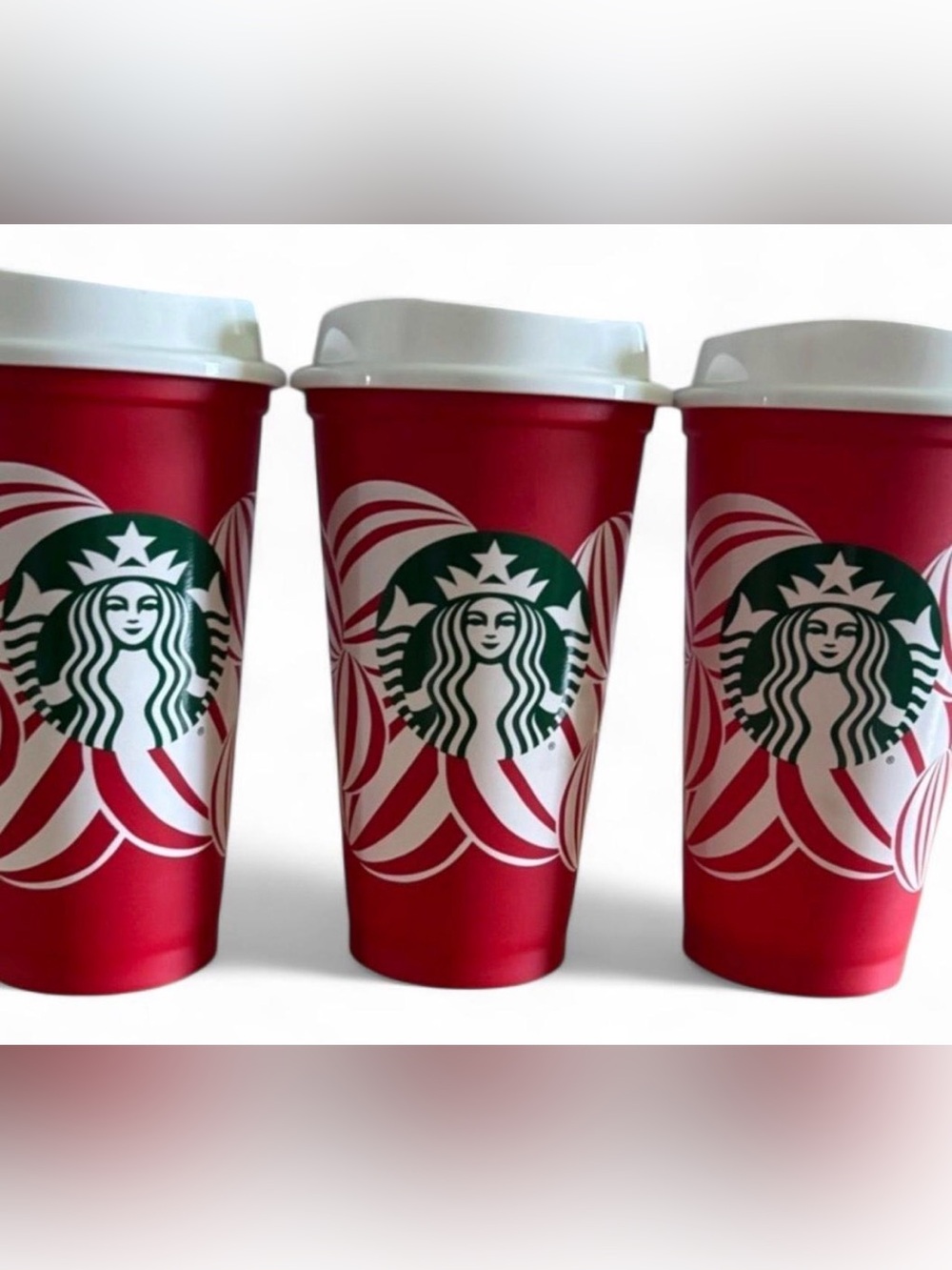 Red Starbucks holiday cups with white peppermint swirl design